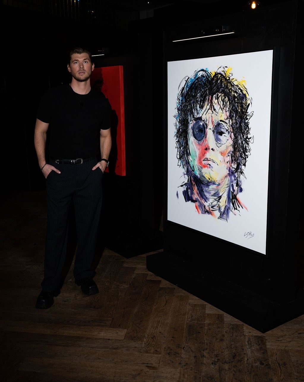 Andrew Leuschke beside one of his colorful gestural portrait paintings